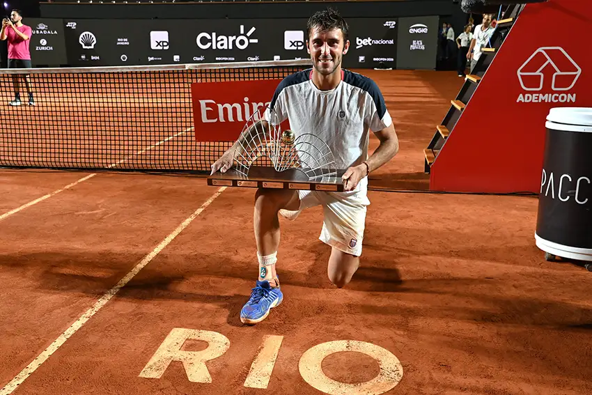 Tomás Etcheverry segurando o troféu de campeão do Rio Open 2026 na quadra central do torneio.