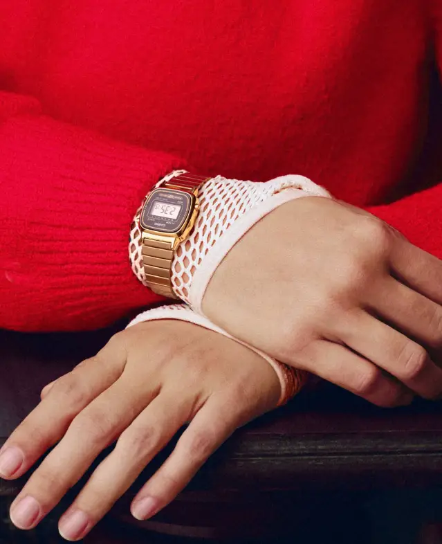 Relógio Casio Vintage dourado em destaque no pulso de uma pessoa, com roupa vermelha e estética contemporânea da campanha Vintage Masterpiece.