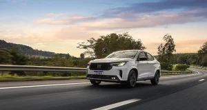 Fiat Fastback branco trafega por uma rodovia durante o pôr do sol, em destaque na campanha de ofertas do Dia D Fiat.