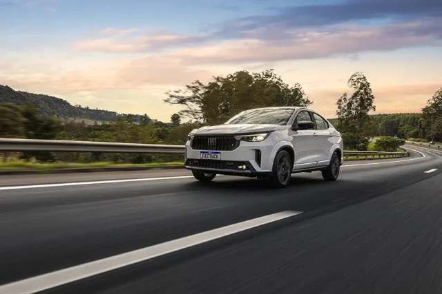 Dia D da Fiat termina hoje com Fastback por R$ 119.990 Fiat Fastback branco trafega por uma rodovia durante o pôr do sol, em destaque na campanha de ofertas do Dia D Fiat.