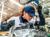 Funcionária da Toyota trabalha na montagem de motor em fábrica da empresa, destacando tecnologia e produção automotiva no Brasil.
