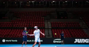 João Fonseca treina na quadra da Copa Davis, com arquibancadas ao fundo, durante preparação para o confronto entre Brasil e Suíça no Rio de Janeiro.