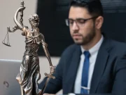 Marketing digital para pequenas empresas: o que a advocacia ensina sobre crescer dentro das regras Advogado em escritório diante de uma estátua da Justiça, representando marketing jurídico e estratégias digitais para escritórios de advocacia.