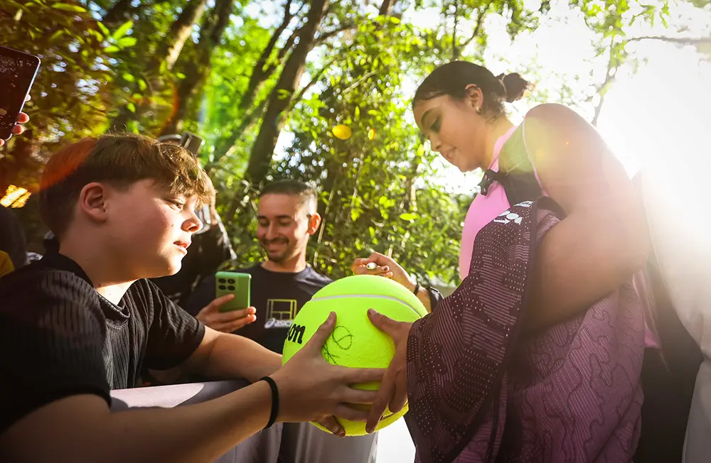 Naná Silva interage com jovens fãs durante o SP Open 2026 e autografa uma bola de tênis gigante.
