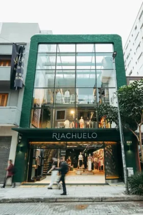 Fachada da loja flagship da Riachuelo na rua Oscar Freire, em S&atilde;o Paulo, com estrutura de vidro e acesso para tr&ecirc;s andares.