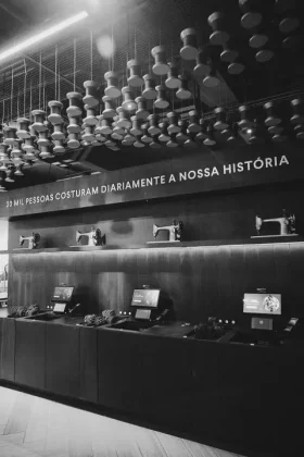 Interior da flagship da Riachuelo na Oscar Freire, em S&atilde;o Paulo, com m&aacute;quinas de costura, caixas de autoatendimento e elementos da hist&oacute;ria da marca.
