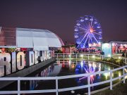 Rio Gastronomia 2026 no Jockey Club, com roda-gigante iluminada, espaços de marcas, área gastronômica e lago refletindo as luzes do evento.