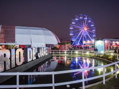 Rio Gastronomia 2026 no Jockey Club, com roda-gigante iluminada, espaços de marcas, área gastronômica e lago refletindo as luzes do evento.