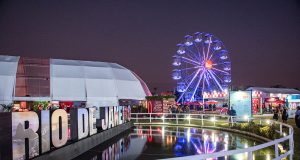 Rio Gastronomia 2026 no Jockey Club, com roda-gigante iluminada, espaços de marcas, área gastronômica e lago refletindo as luzes do evento.