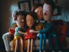 Família reunida em casa, sentada no sofá, em cena de animação que representa união, acolhimento e convivência familiar.
