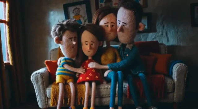 Casa Ronald McDonald Brasil lança nova campanha com conceito “O cuidado mora aqui” Família reunida em casa, sentada no sofá, em cena de animação que representa união, acolhimento e convivência familiar.