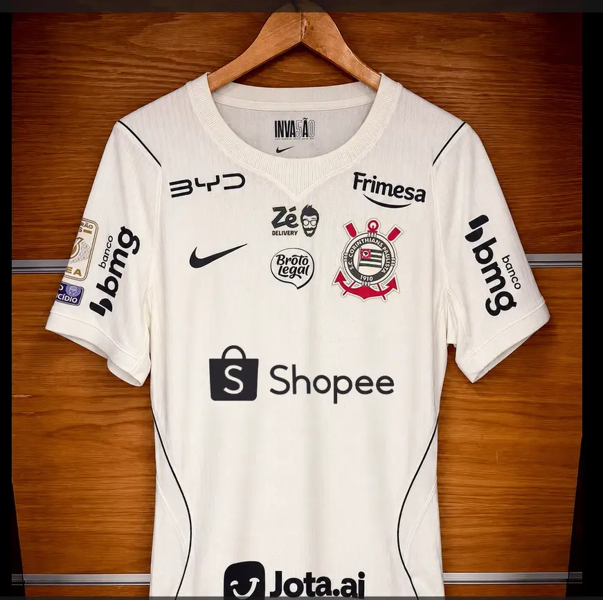 Camisa branca do Corinthians com o logotipo da Shopee como patrocinadora máster, além das marcas BYD, Frimesa, Banco Bmg e Jota.ai.