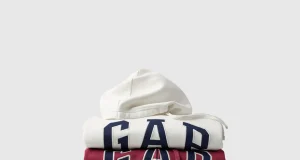 Pilhas de moletons com capuz da Gap em diferentes cores, incluindo branco, vermelho, verde, azul e cinza, com o logotipo da marca em destaque, para a campanha Hoodie Day na Dafiti.