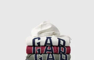Pilhas de moletons com capuz da Gap em diferentes cores, incluindo branco, vermelho, verde, azul e cinza, com o logotipo da marca em destaque, para a campanha Hoodie Day na Dafiti.