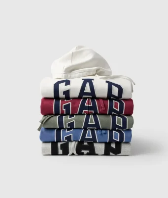 Pilhas de moletons com capuz da Gap em diferentes cores, incluindo branco, vermelho, verde, azul e cinza, com o logotipo da marca em destaque, para a campanha Hoodie Day na Dafiti.