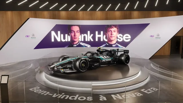 Carro da Mercedes-AMG PETRONAS F1 Team em exposição na Nubank House, com painel dos pilotos e identidade visual da parceria entre Nubank e a equipe de Fórmula 1.