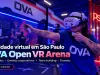 OVA Open VR Mulher usando óculos de realidade virtual na OVA Open VR Arena, em São Paulo, com área de jogos, PS Zone e outros participantes ao fundo.