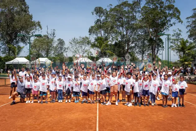 Grupo de crian&ccedil;as e jovens re&uacute;ne-se na quadra de t&ecirc;nis para celebrar a participa&ccedil;&atilde;o em iniciativa social apoiada pelo Rio Open.