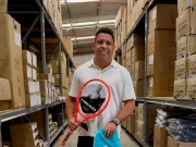 Ronaldo Fenômeno segura uma raquete de tênis HEAD e uma bolsa esportiva da marca em um depósito com produtos e caixas da fabricante.